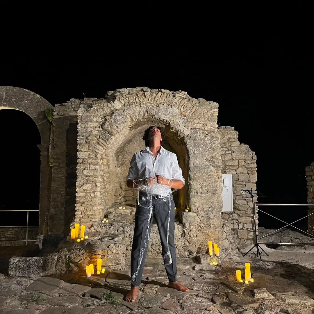 Daniel Cundari in scena di notte sotto un arco di pietra